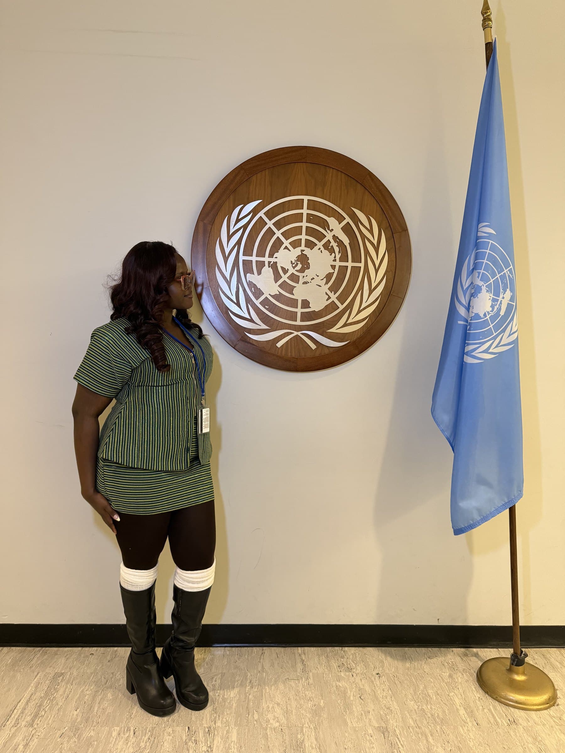 Taslemat Yusuf beside the UN emblem and flag